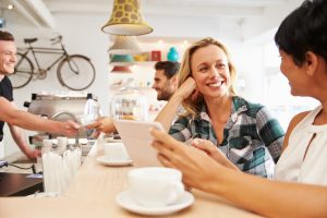 Two women at a meeting in a cafe holding a digital tablet