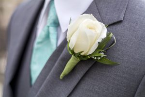 rose boutonniere for wedding or prom on a male with a blue tie
